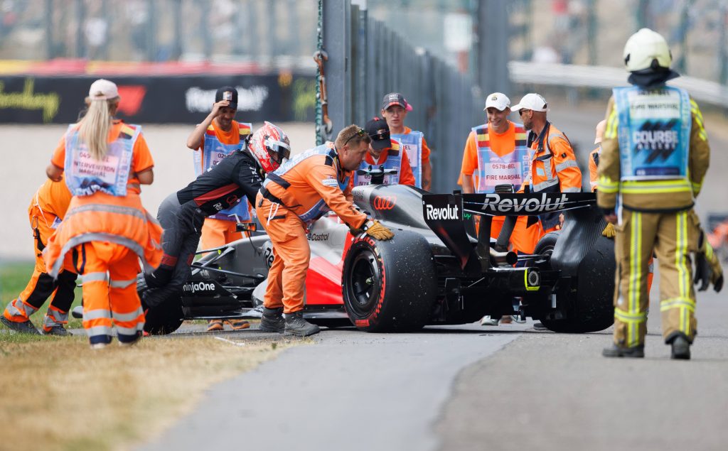 Hülkenberg schiebt sein Auto mit den Marshalls von der Strecke